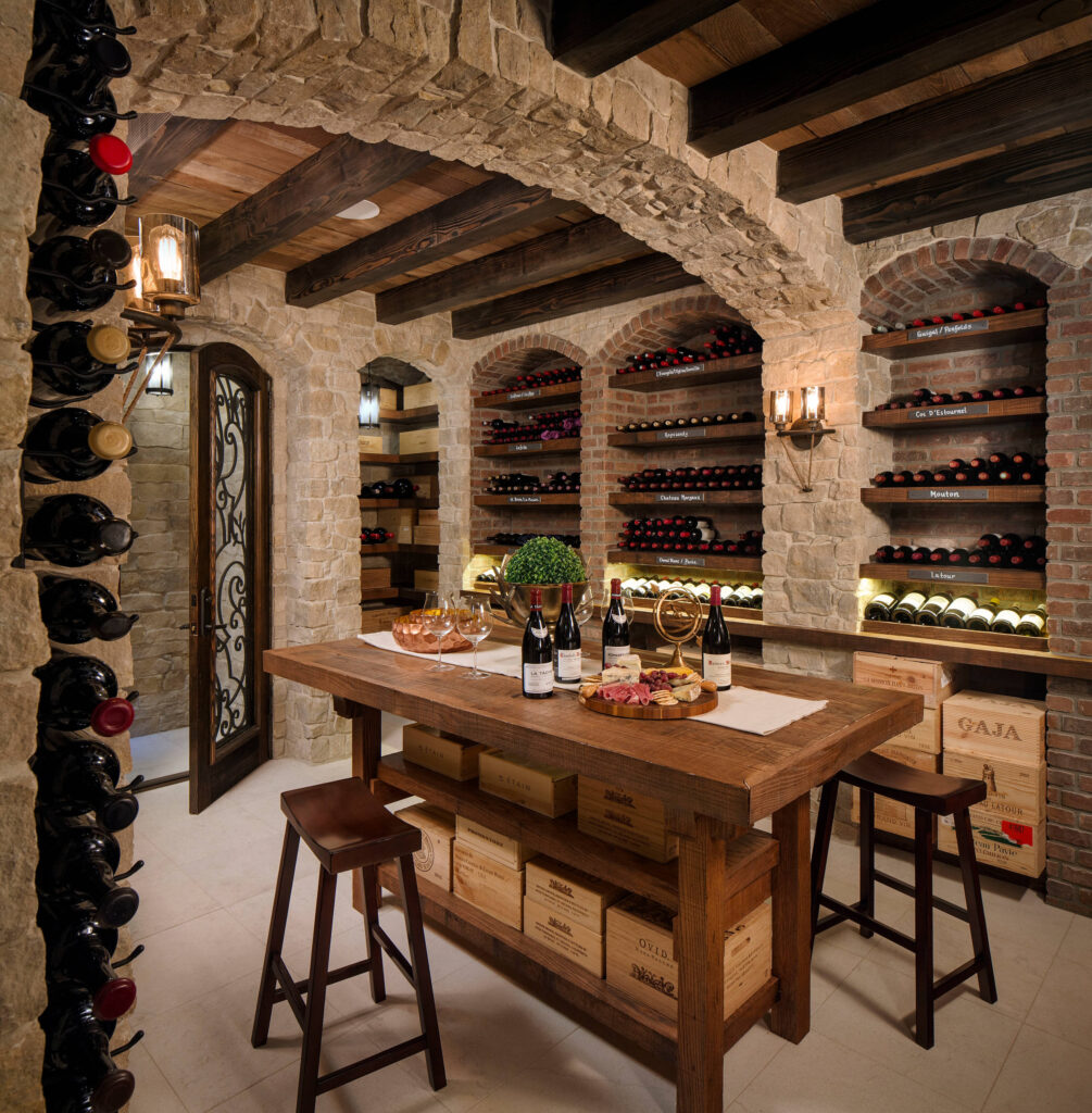 Stone and brick wine cellar with arched alcoves, wooden beam ceiling, and labeled wine shelves