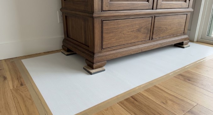 Wood armoire on sliders over taped floor protection
