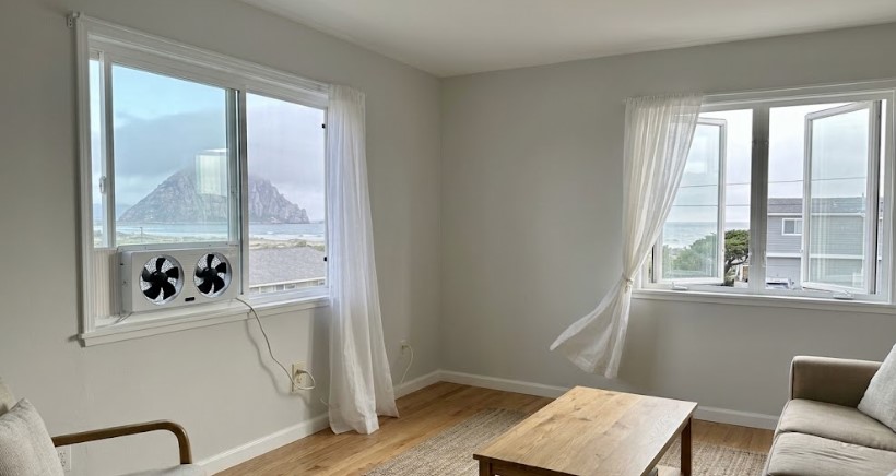 Painted living room with window fan and open windows facing Morro Rock