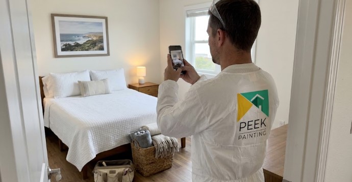 Painter photographing a bedroom before moving furniture