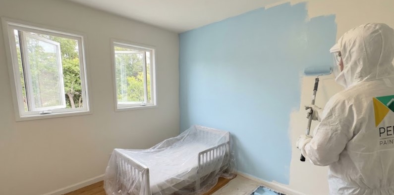 Peek painter rolling blue paint in a child's bedroom with windows open