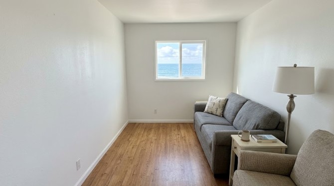 Small ocean-view room with white walls and gray sofa